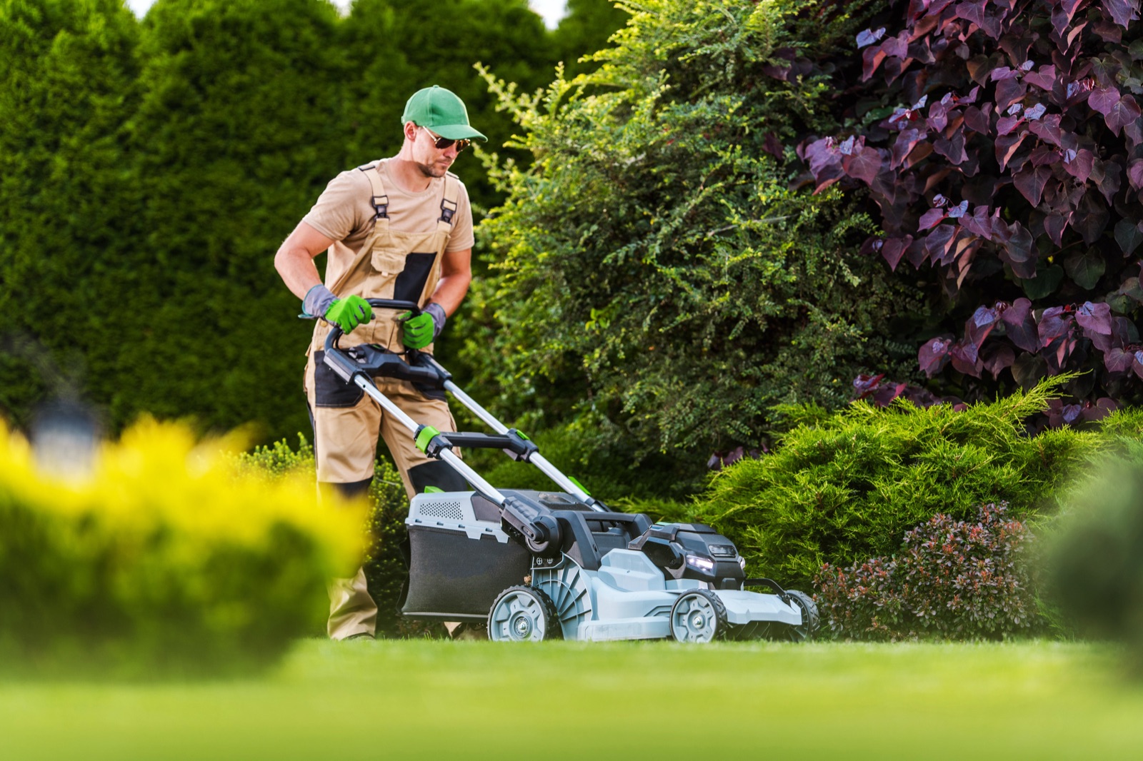 Salarié tondant une pelouse dans un jardin